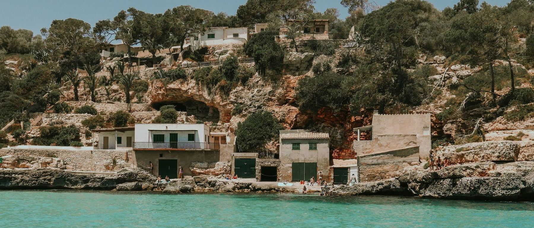 Häuser und Bootshäuser in einer Bucht auf Mallorca