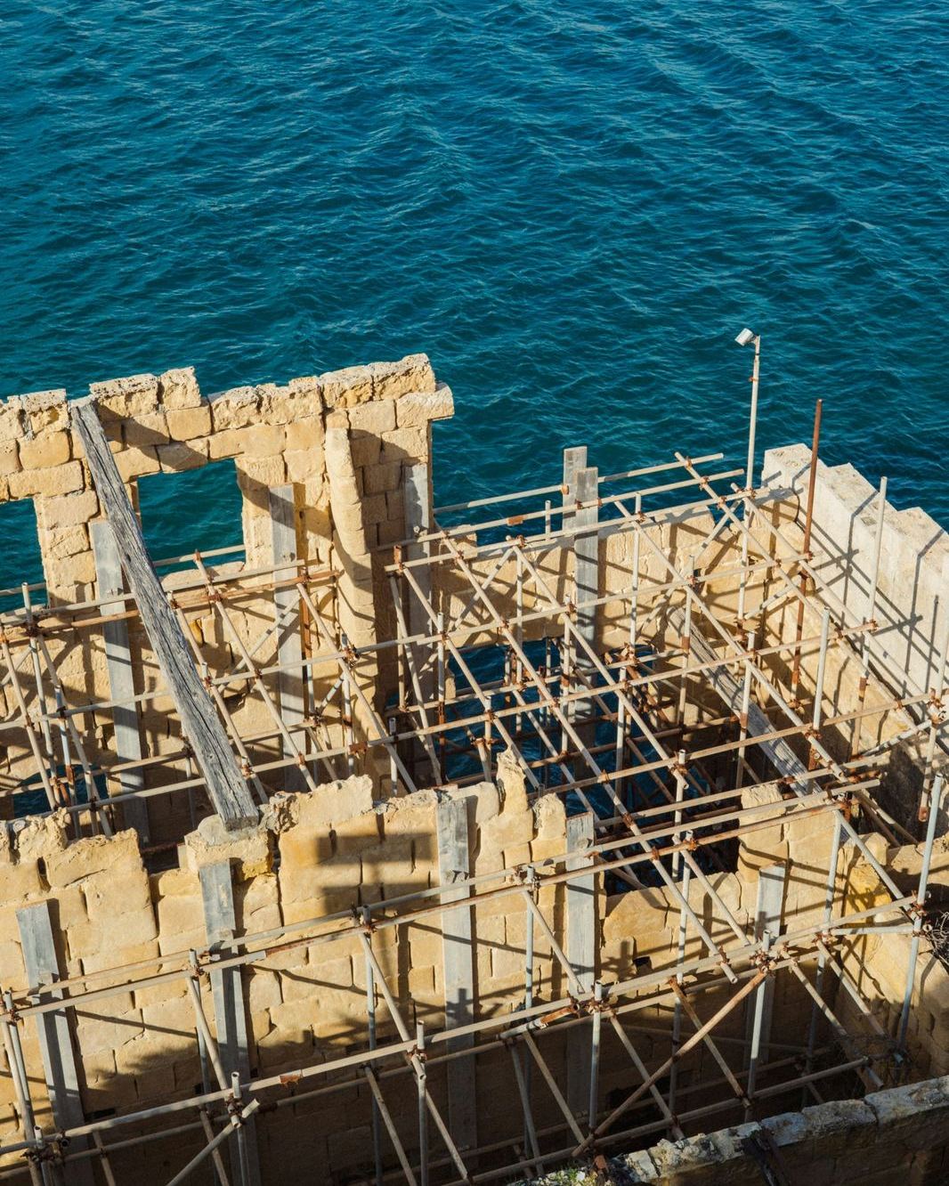 Sandsteinmauern mit Gerüst am Meer während einer Sanierung